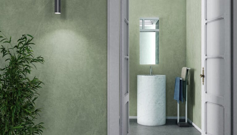 Pale green bathroom walls finished with Rialto Epoca Marmo lime plaster, featuring a white pedestal sink area