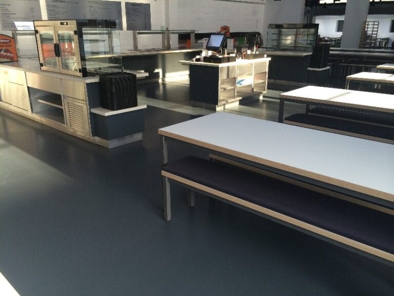 Commercial cafeteria interior with dark floor finish, six months after application