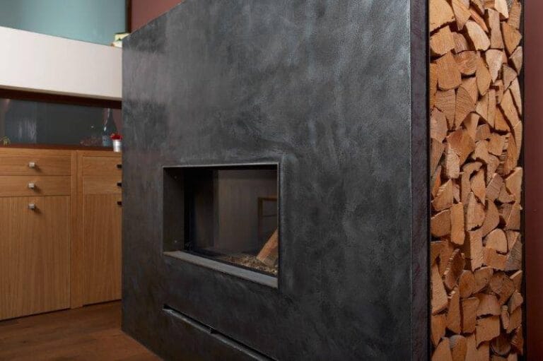 Dark Microcement fireplace surround with firewood storage beside