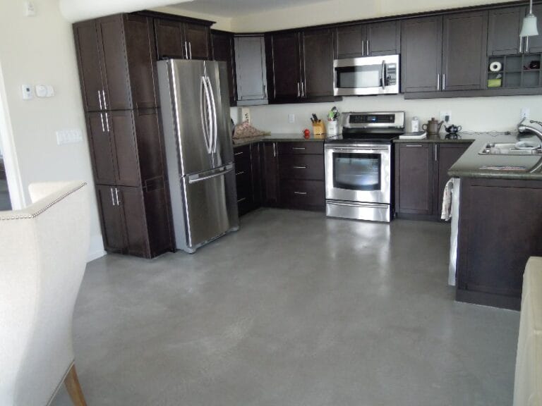 Grey Microcement floor in modern kitchen with dark fitted cabinetry