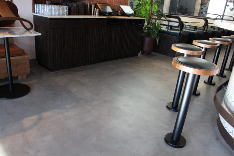 Politura Microcement floor with decorative animal sculptures in minimalist restaurant interior