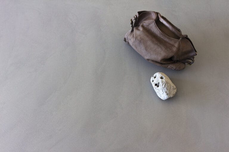 ErreLAB Pietra Continua Basalto cream stone floor with leather bag and textured stone styling elements