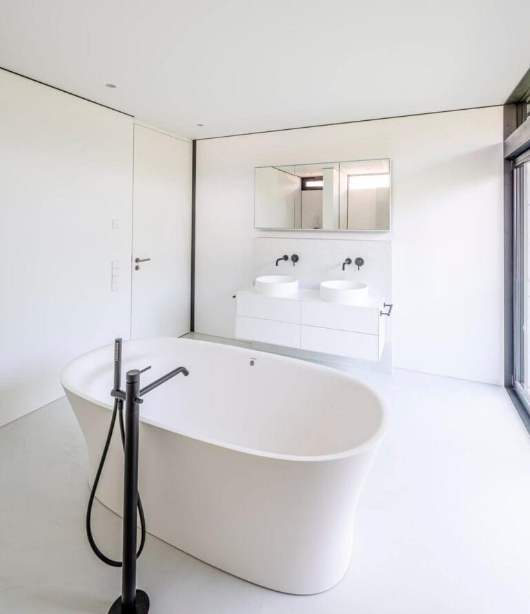 ErreLAB Pietra Continua Basalto resin floor in a bathroom with a double vanity and freestanding bath