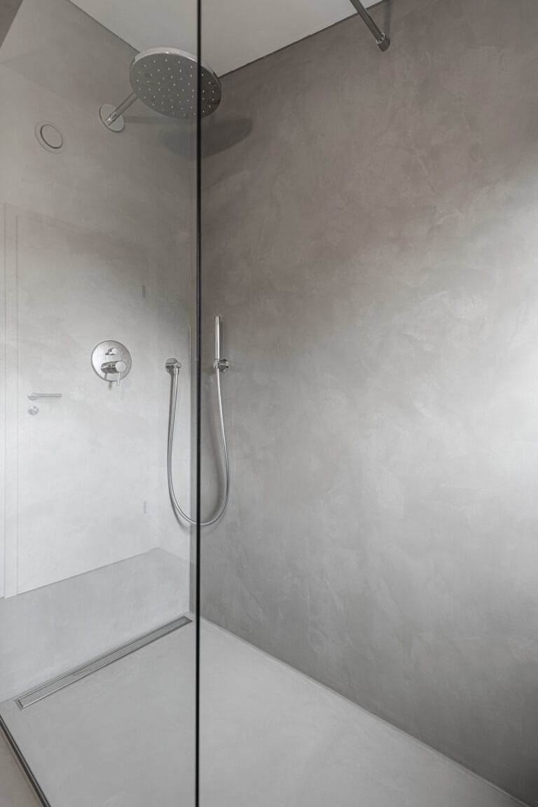 ErreLAB Pietra Continua Basalto walk-in shower behind a glass screen, with a linear floor drain