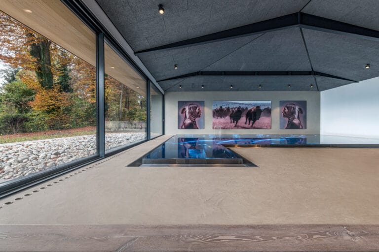 Indoor pool surround with ErreLAB Pietra Continua Calcare flooring, lake views visible from glazed walls