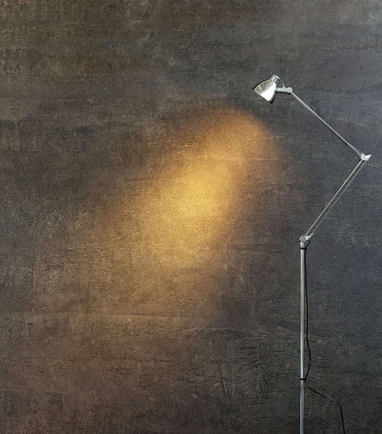 ErreLAB Pietra Continua Porfido wall lit dramatically by floor lamp