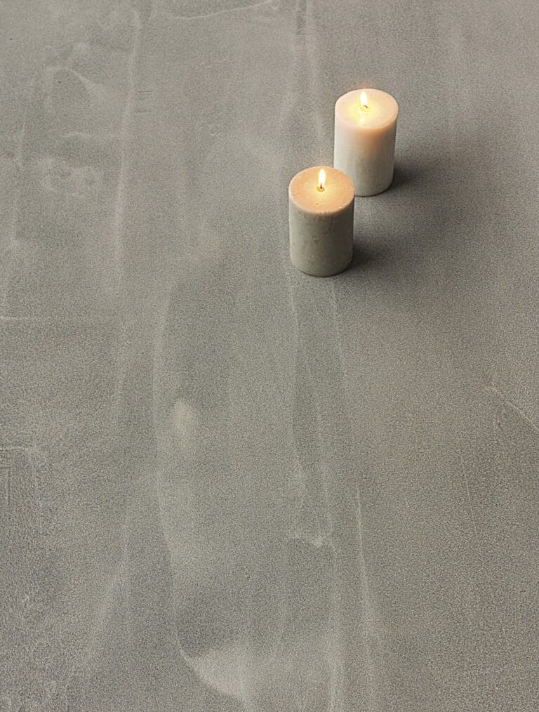 Two lit candles on ErreLAB Pietra Continua Quarzite slate grey textured surface