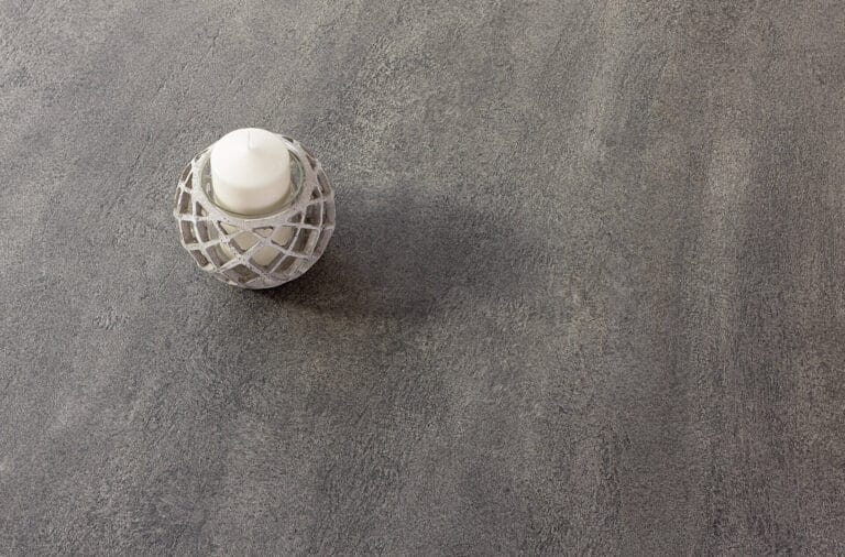 White candle with macramé holder on ErreLAB Pietra Continua Scisto dark textured surface