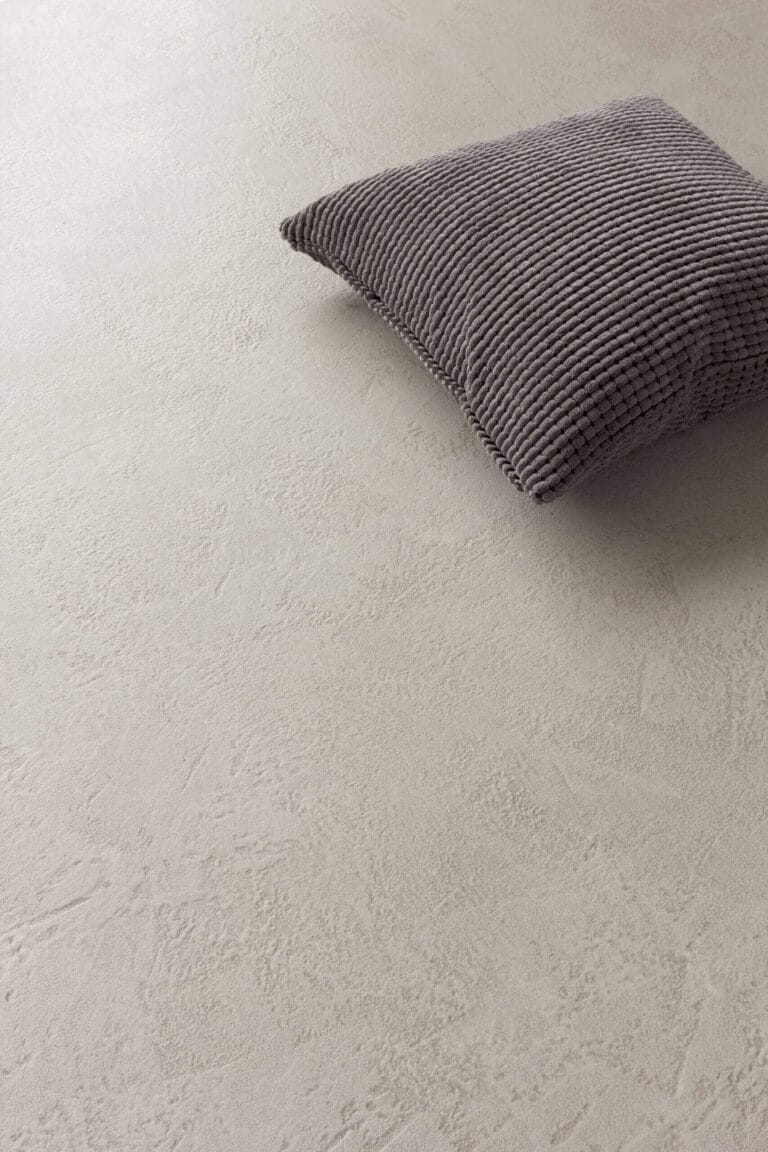 Grey knit cushion placed on ErreLAB Pietra Continua Travertino textured wall surface