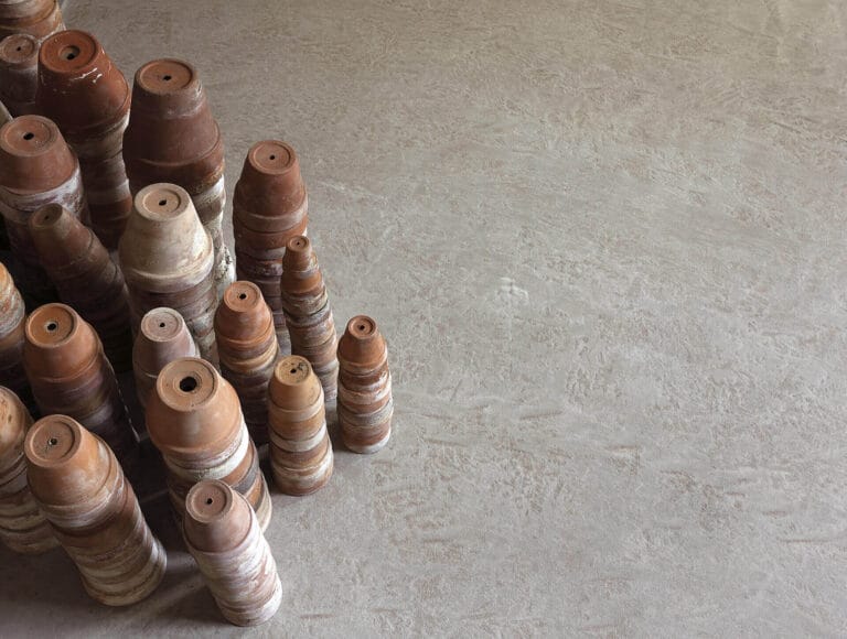 Spray samples and test cans displayed on ErreLAB Pietra Continua Travertino textured surface
