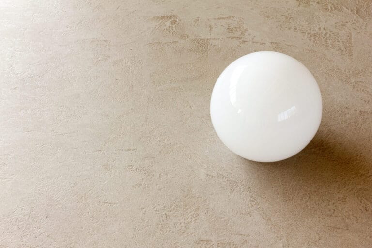 Close-up detail of ErreLAB Pietra Continua Travertino textured surface with white spherical object