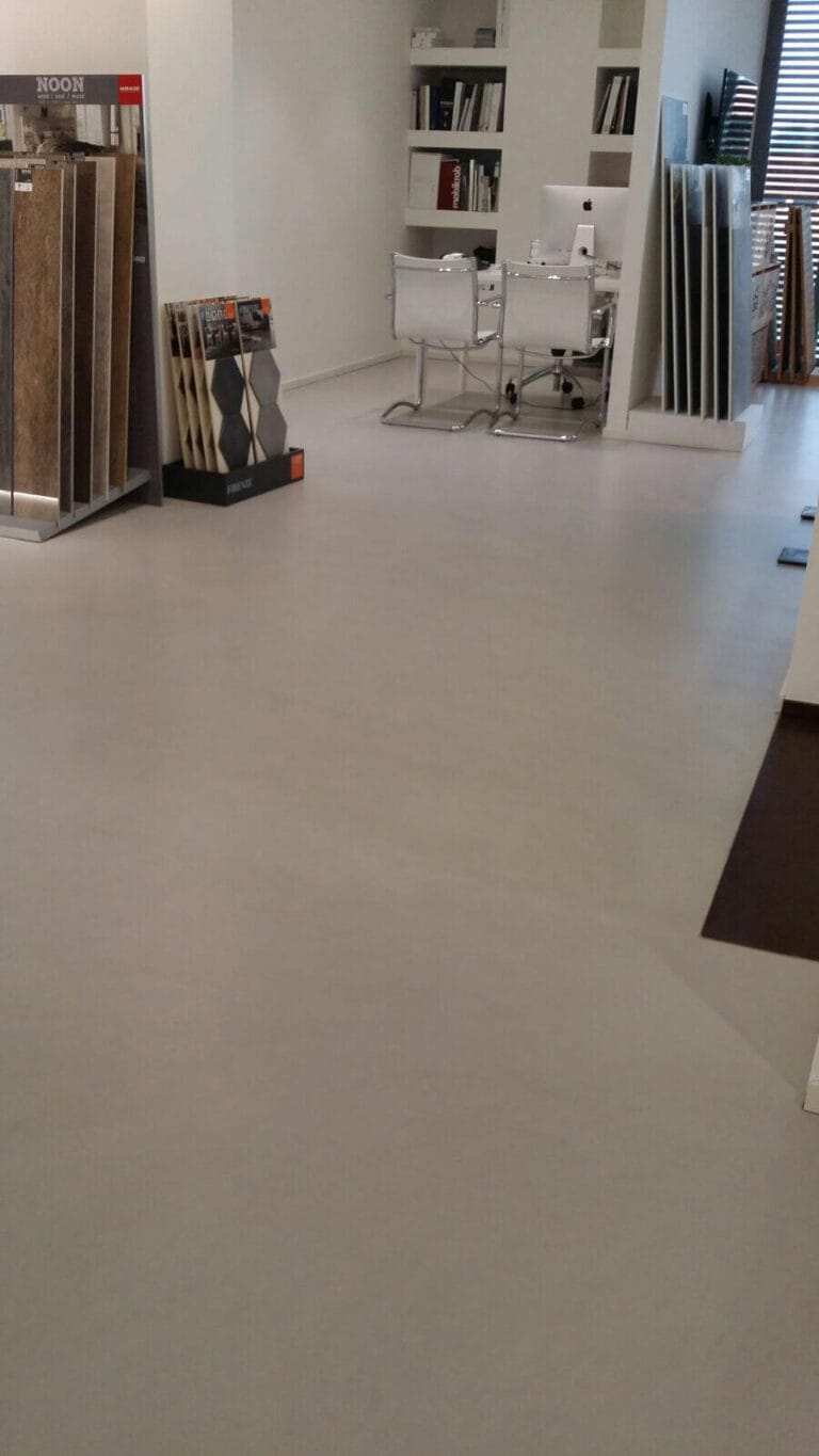 ErreLAB Spatolato cream resin flooring in a showroom displaying tools and decorative items