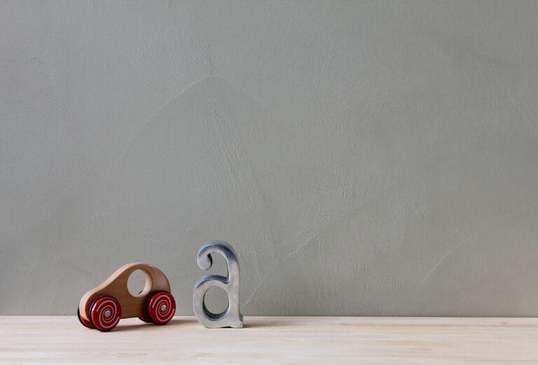 Pale grey ErreLAB Spatolato wall finish with small red toy car and white accessories