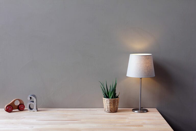 Pale grey ErreLAB Spatolato wall finish in workspace setting with desk lamp and plant