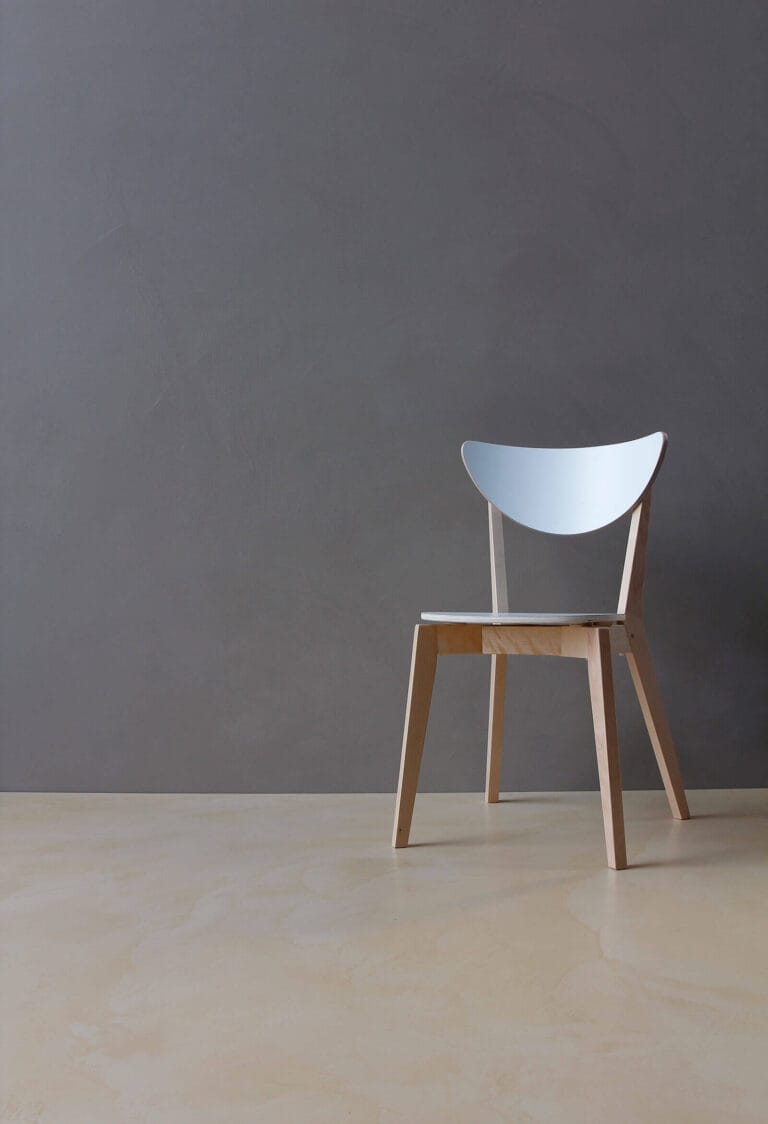 Dark grey ErreLAB Spatolato wall finish with white wooden stool in front