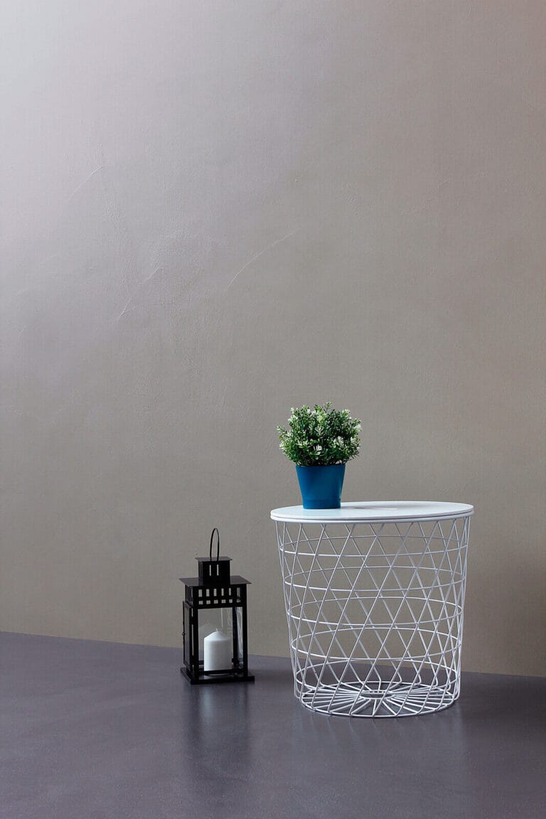 ErreLAB Spatolato resin wall finish in light grey, styled with potted plant and wire basket