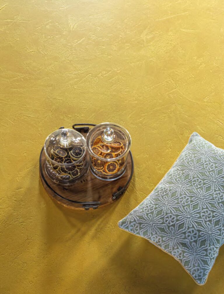 ErreLAB Metallo Continuo floor in gold with a cushion and glass jars
